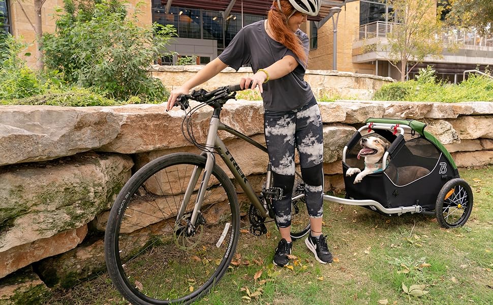 woman with bike looking back at dog in pet bike trailer